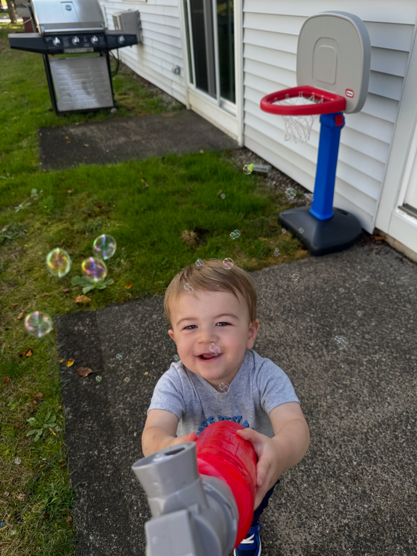 Brayden grinning in the driveway, surrounded by soap bubbles on a sunny afternoon
